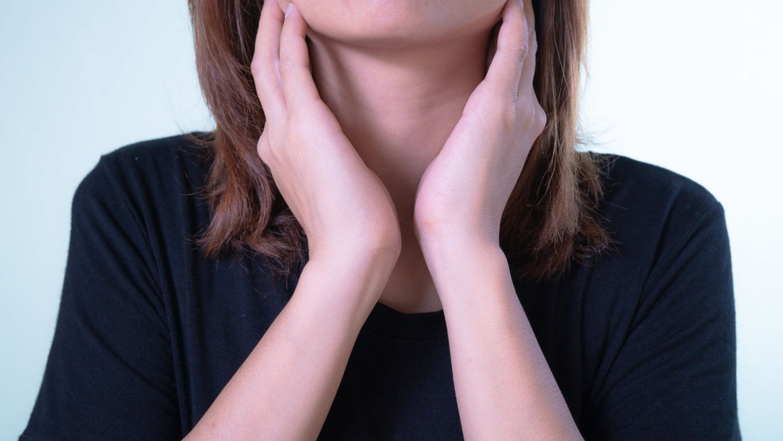 Woman with her hands at the base of her throat