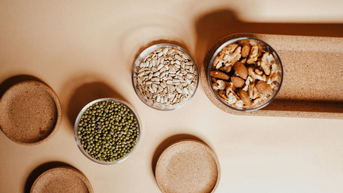 Bowls of seeds and a jar of nuts on a counter