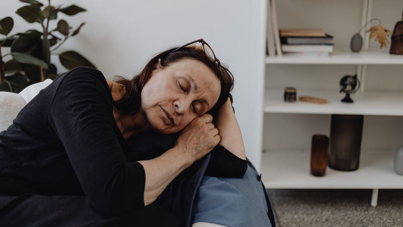 Tired woman in her fifties asleep on the sofa in the middle of the day