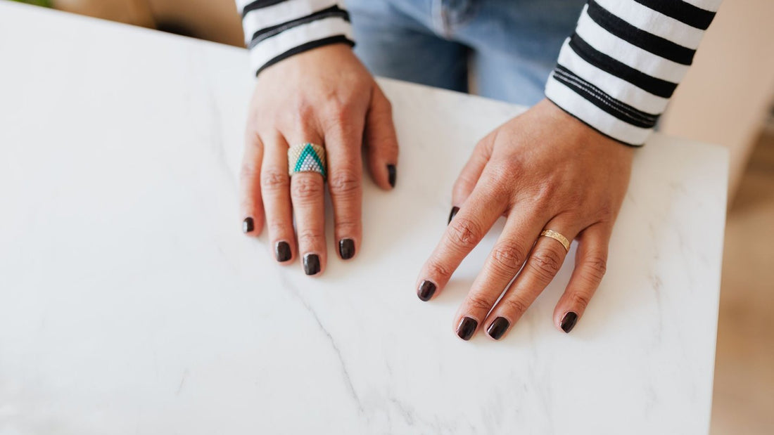 Hands with dark painted nails resting on a marble table