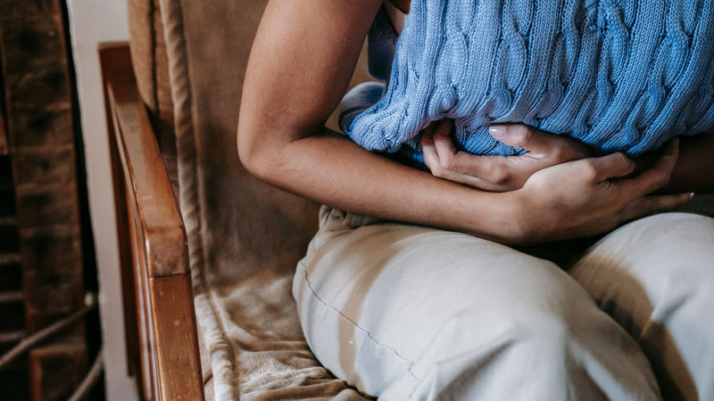 Woman holding a pillow against her bloated stomach